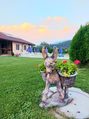 a statue of a dog holding two flower baskets at Вилен комплекс Дарибел in Sapareva Banya