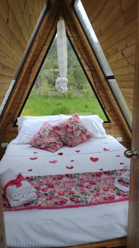 Una cama en una tienda con flores. en VILLA DE LOS ANGELES GLAMPING, en Anolaima