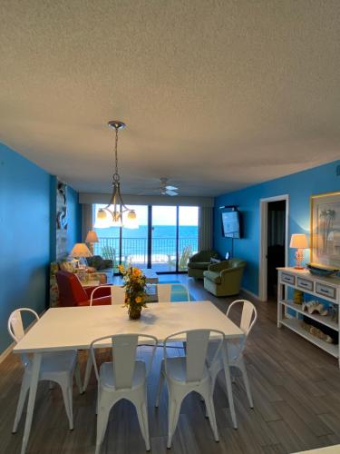 a living room with a table and chairs and the ocean at Updated Condo. Great for families. Seaside Beach and Racquet Club 5717 in Orange Beach