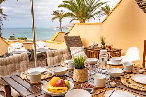 a table with food on a balcony with the ocean in the background at casamarena in Costa Calma
