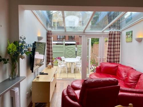 a living room with a red couch and a table at Somers 4 bed House off road parking pet friendly in Portsmouth