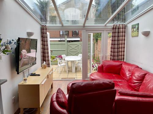 a living room with a red leather couch and a tv at Somers 4 bed House off road parking pet friendly in Portsmouth