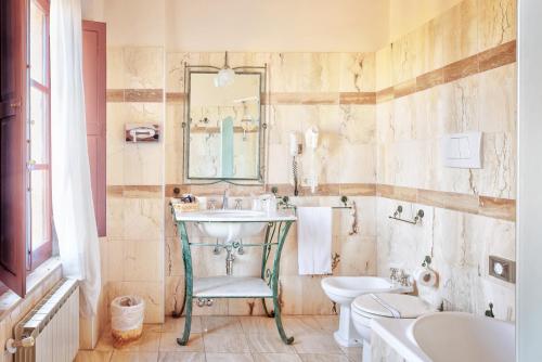 a bathroom with a sink and a toilet and a mirror at Hotel Borgo Casabianca in Serre di Rapolano