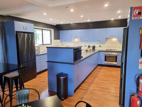 a kitchen with blue cabinets and a black refrigerator at Blue Wren Lodge Waratah in Newcastle