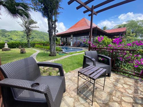 a patio with two chairs and a table at Tropical Balinese Villa Atenas in Escobal