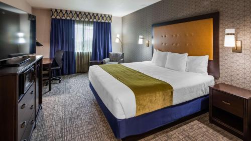um quarto de hotel com uma cama, uma secretária e uma televisão em Best Western Plus Grant Creek Inn em Missoula