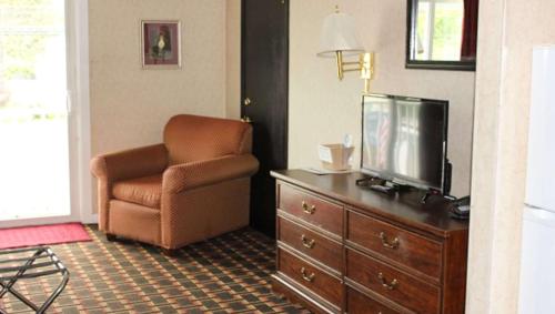 a living room with a chair and a television on a dresser at Colonial Inn Ellsworth in Ellsworth