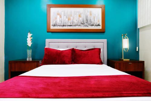 a bedroom with a bed with red pillows and a blue wall at Victoria City Hotel in Oranjestad