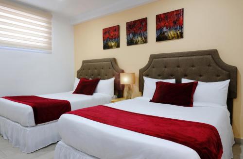 two beds in a hotel room with red pillows at Victoria City Hotel in Oranjestad