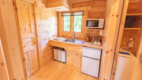 eine Küche in einem Blockhaus mit einer Spüle und einer Mikrowelle in der Unterkunft ロガシス石垣野底ヴィラ in Ibaruma