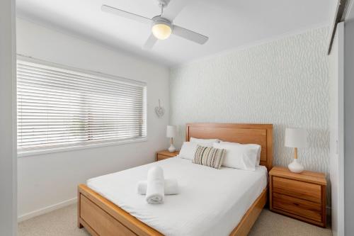 a bedroom with a bed with white sheets and a window at Culgoa Point Beach Resort in Noosa Heads