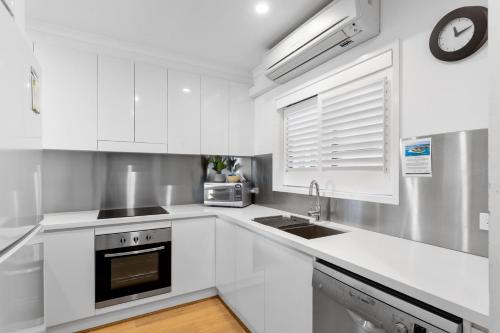 a white kitchen with a sink and a microwave at Culgoa Point Beach Resort in Noosa Heads