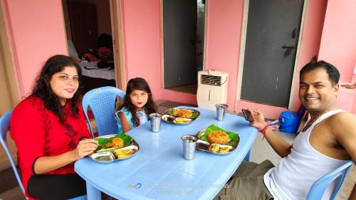 a man and a woman sitting at a table with food at Abhi Homestay Hampi in Hampi
