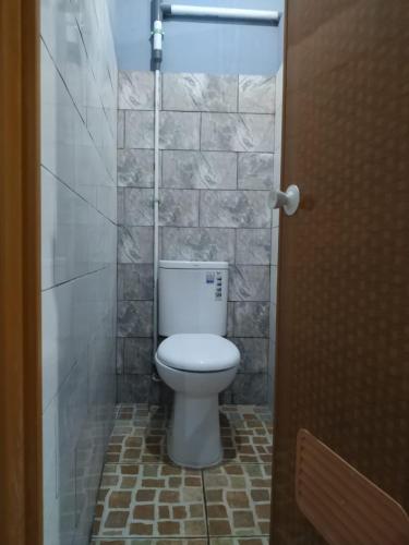a bathroom with a toilet in a tiled room at Eiffel Residence Petojo - Female Only in Jakarta
