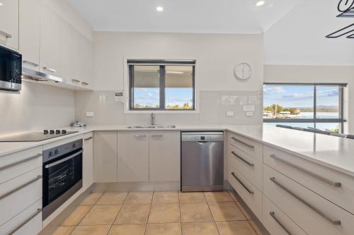 a white kitchen with a sink and a dishwasher at Culgoa Point Beach Resort in Noosa Heads