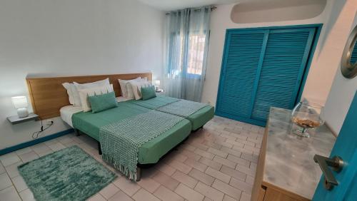 una camera da letto con un letto con un piumone verde di Casa da Praia by Sunny Deluxe ad Albufeira
