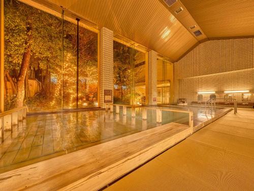 a swimming pool in a building with a large window at Yukai Resort Premium Awazu Grand Hotel in Komatsu