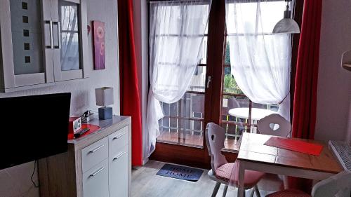 une cuisine avec une table et une fenêtre avec des rideaux rouges dans l'établissement Ferienwohnung Sweety Haus Sachsensteinblick, à Bad Sachsa