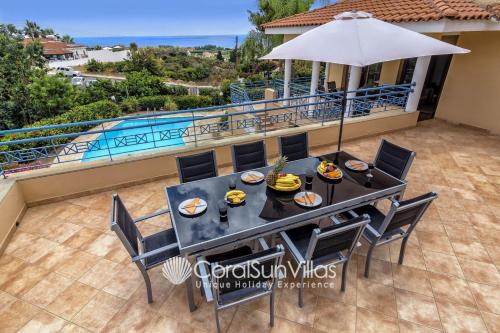 a dining table with chairs and an umbrella on a patio at Zeus Sublime Villa 5 bedrms HEATED POOL by Coral Sun Villas, in Coral Bay