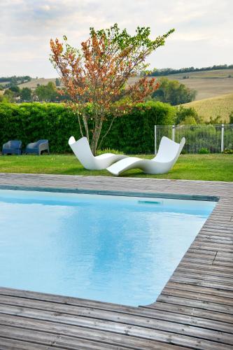 two white chairs sitting next to a swimming pool at En Marge in Aureville