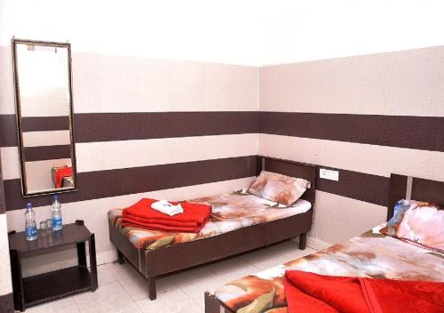 a small room with a bed and a mirror at Asha Guest House in Amritsar
