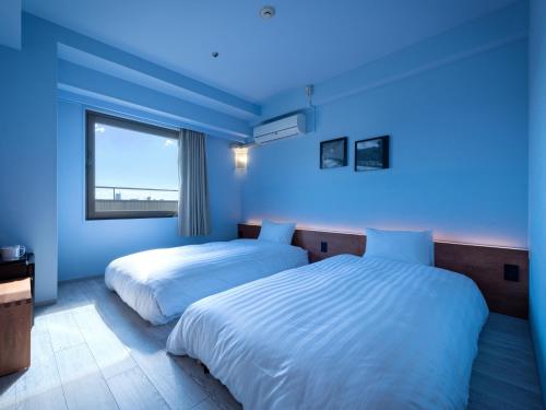 two beds in a blue room with a window at EN HOTEL Kyoto in Kyoto