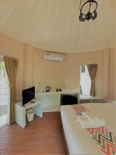 a bedroom with a bed and a desk and a television at Saffron On The Sea Resort in Ko Chang