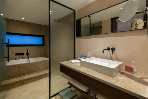 a bathroom with a large sink and a tub at Mövenpick Hotel Gammarth Tunis in Gammarth