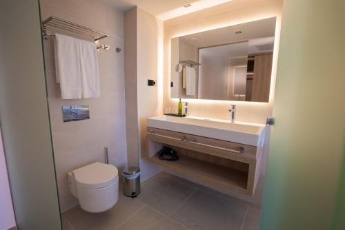 a bathroom with a sink and a toilet and a mirror at Hotel Morlans Suites - Adults Only in Paguera