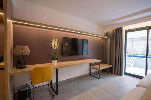 a room with a desk with a tv on a wall at Hotel Morlans Suites - Adults Only in Paguera