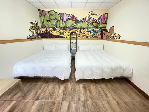 two beds in a room with a mural on the wall at 鳳奶客棧 in Changbin