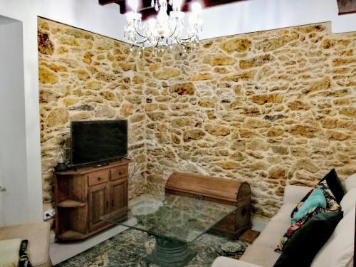 a living room with a stone wall with a tv at A Mercé in Pobra do Caramiñal