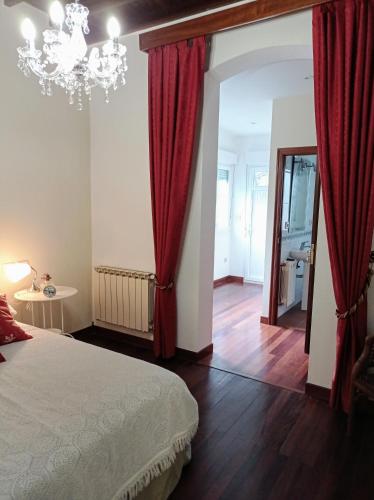 a bedroom with a bed with red curtains and a chandelier at A Mercé in A Pobra do Caramiñal