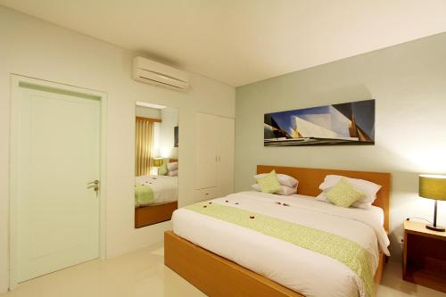 a bedroom with a large bed and a mirror at Apple Suite in Kerobokan