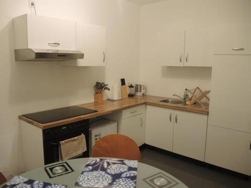 a small kitchen with white cabinets and a table at Wohnwerk41 in Schwäbisch Hall