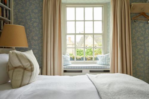 a bedroom with a bed and a window with a bench at The Kingham Plough in Kingham