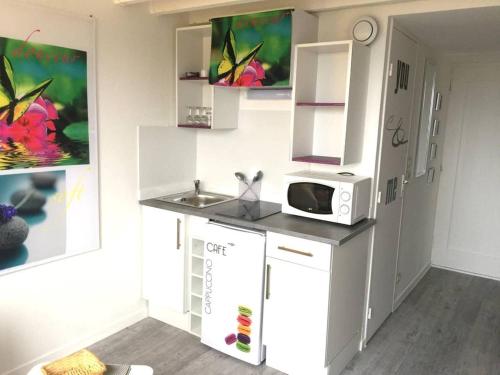 une petite cuisine avec un micro-ondes et un évier dans l'établissement Très joli duplex Port Crouesty Morbihan, à Arzon