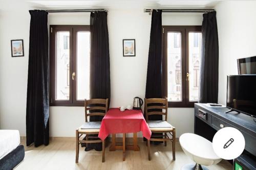 um quarto com uma mesa com cadeiras e uma toalha de mesa vermelha em Blu Suite em Veneza