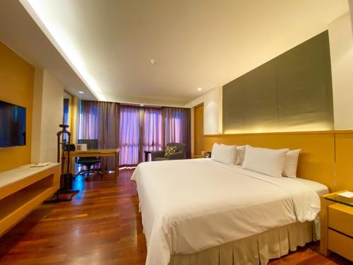 a hotel room with a large white bed and a desk at Lao Plaza Hotel in Vientiane