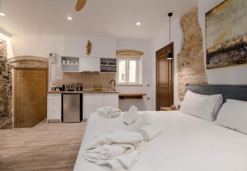 a bedroom with a white bed with towels on it at Curcumelli Luxury Suites - ΠΟΡΤΟΝΙ 1 in Corfu Town
