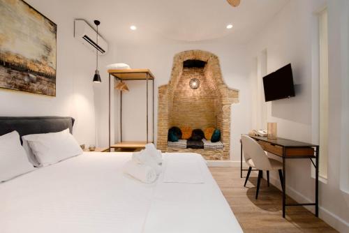 a bedroom with a bed and a desk and a fireplace at Curcumelli Luxury Suites - ΠΟΡΤΟΝΙ 1 in Corfu