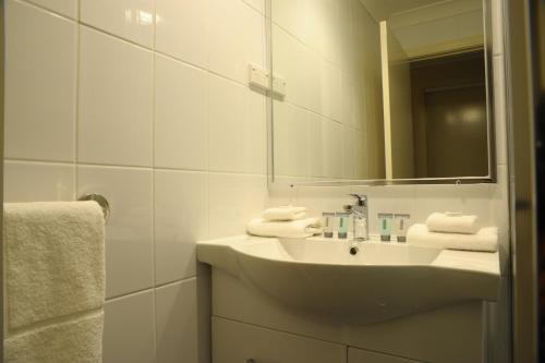 a white sink sitting under a mirror in a bathroom at Havannah Accommodation in Bathurst