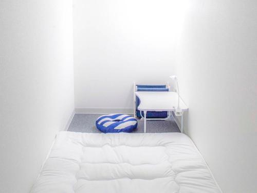 Guesthouse Ise Futami في إيسي: سرير أبيض وكرسي في الغرفة