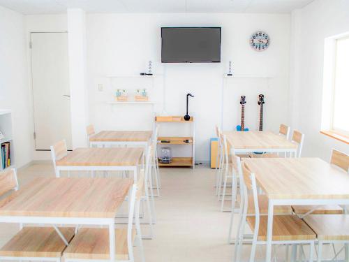 a classroom with tables and a tv on the wall at Guesthouse Ise Futami in Ise