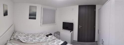 ein kleines Schlafzimmer mit einem Bett und einem TV in der Unterkunft Nyíl Apartmanház in Orfű