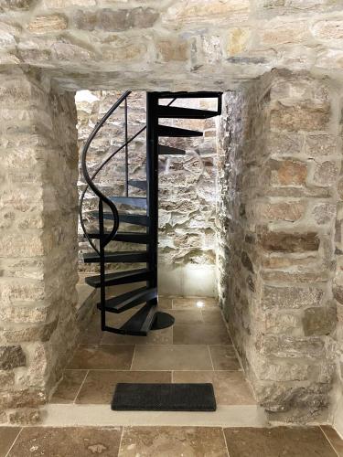 a spiral staircase in a stone building with a brick wall at La Maison des Vendangeurs - TABLE D'HÔTES le soir du jeudi au dimanche- Jacuzzi - Balnéo SPA - ACCES PISCINE pour toutes les chambres sauf STUDIO COQUET- Piscine de mai à mi-octobre in Martignargues