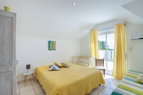 a bedroom with a yellow bed and a balcony at La Villa Bel Océan - Saint Gilles Bains in Saint-Gilles les Bains