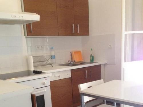 cocina con armarios de madera, fregadero y mesa en Kalliste - Appartement centre ville tout équipé en Bastia