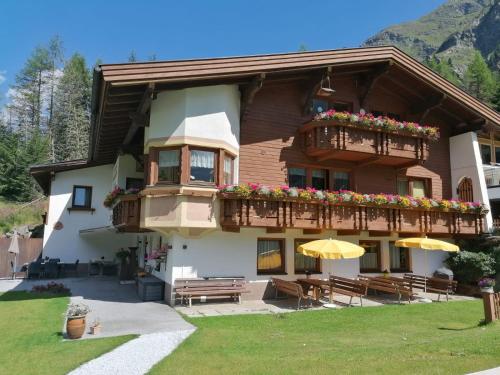 a building with a balcony with flowers and umbrellas at Schusslerhof in Sankt Leonhard im Pitztal