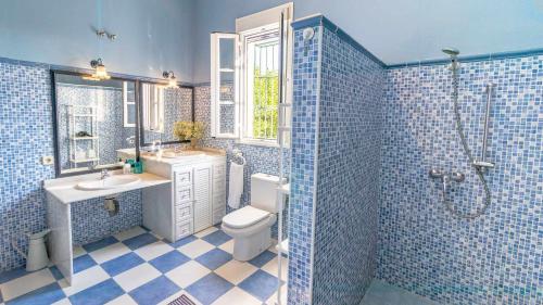 Baño de azulejos azules con aseo y lavamanos en Casa Rural Santa Ana, en Marchena